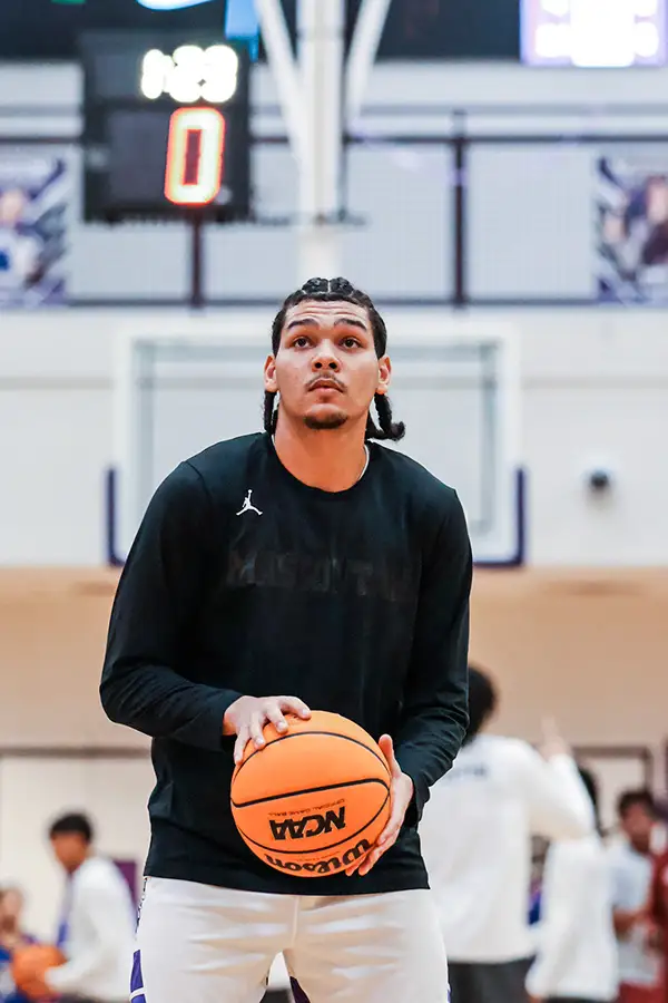 Basketball player in black warm-ups holding the ball at the free-throw line