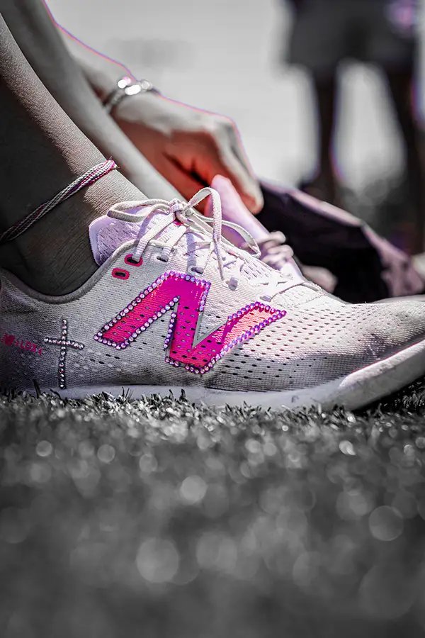 Close-up of a hand lacing a pink and white running shoe