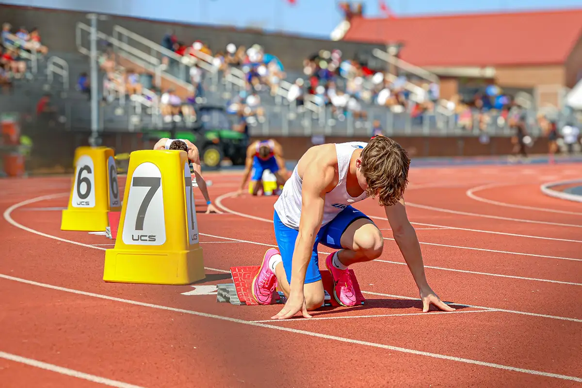 Sprinter settling into the blocks on a red outdoor track