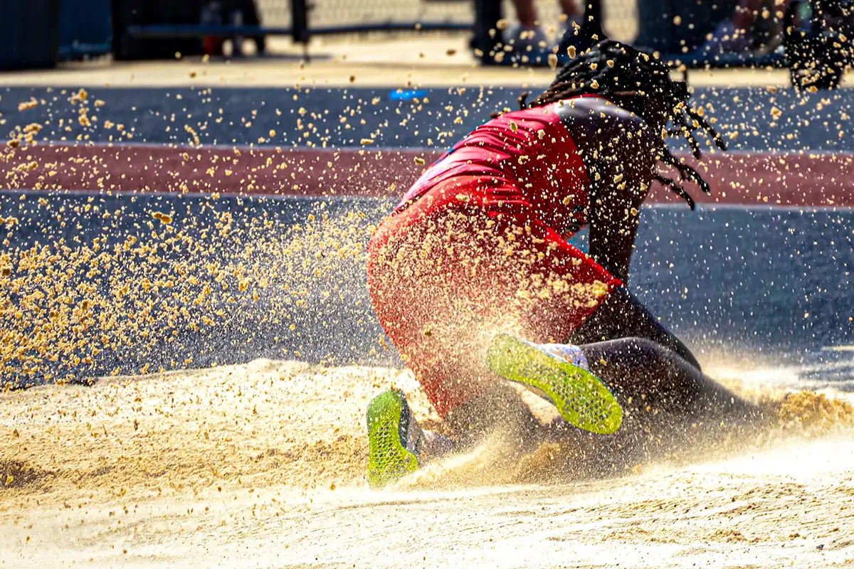 Long jumper hitting the pit low, sand flying in every direction