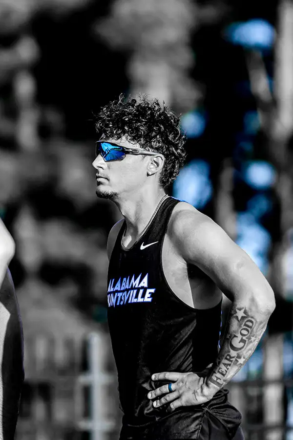 Black-and-white portrait of a runner in sunglasses, hands on hips
