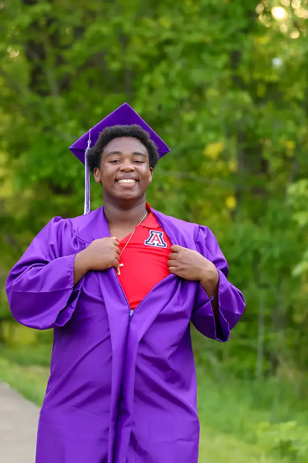 Graduate in a purple gown opening it to show a red shirt