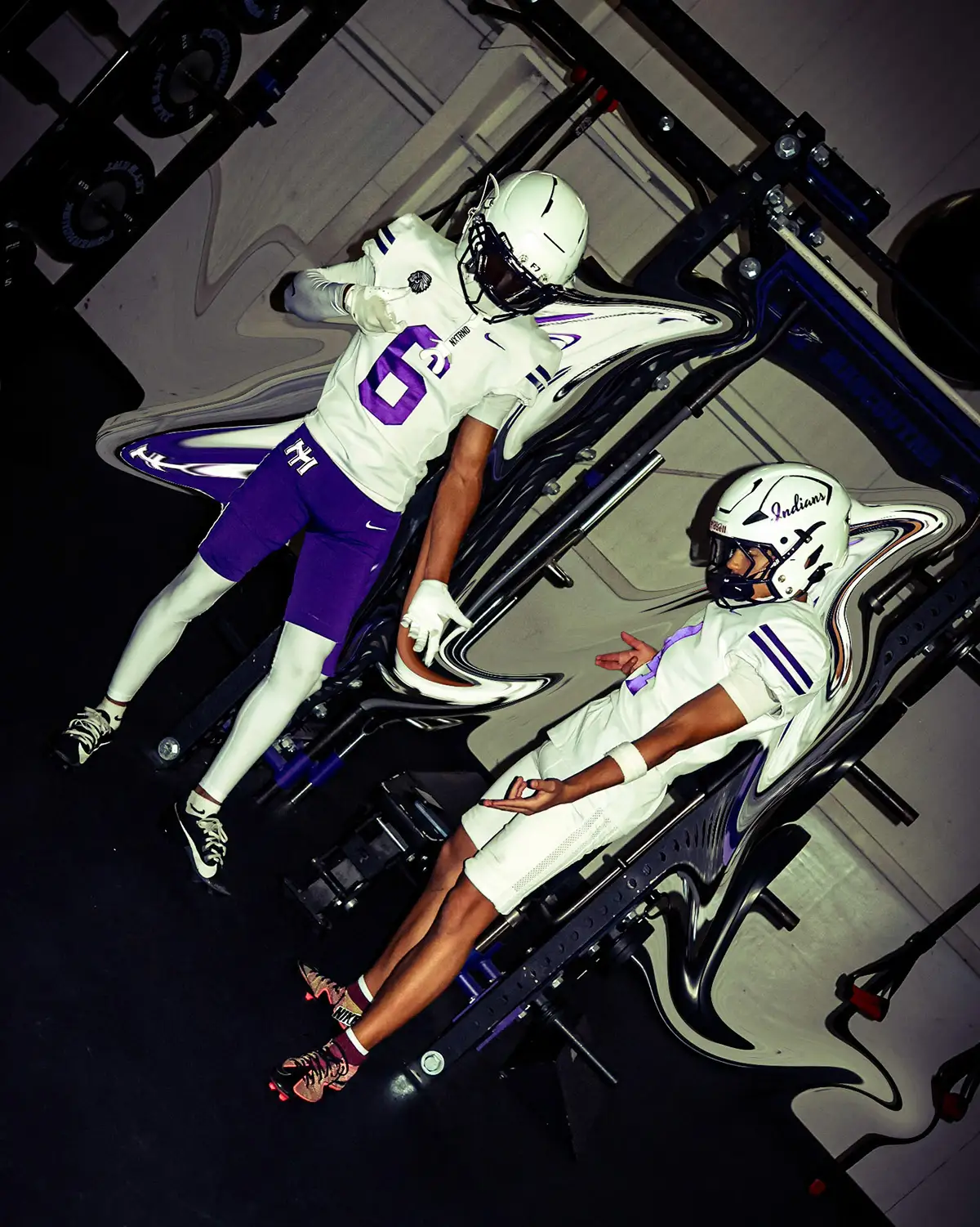 Two football players posed on a tilted frame in a weight room