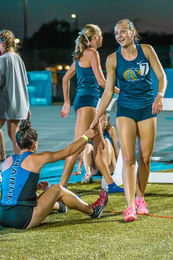 Runners helping a teammate up from the grass after a race
