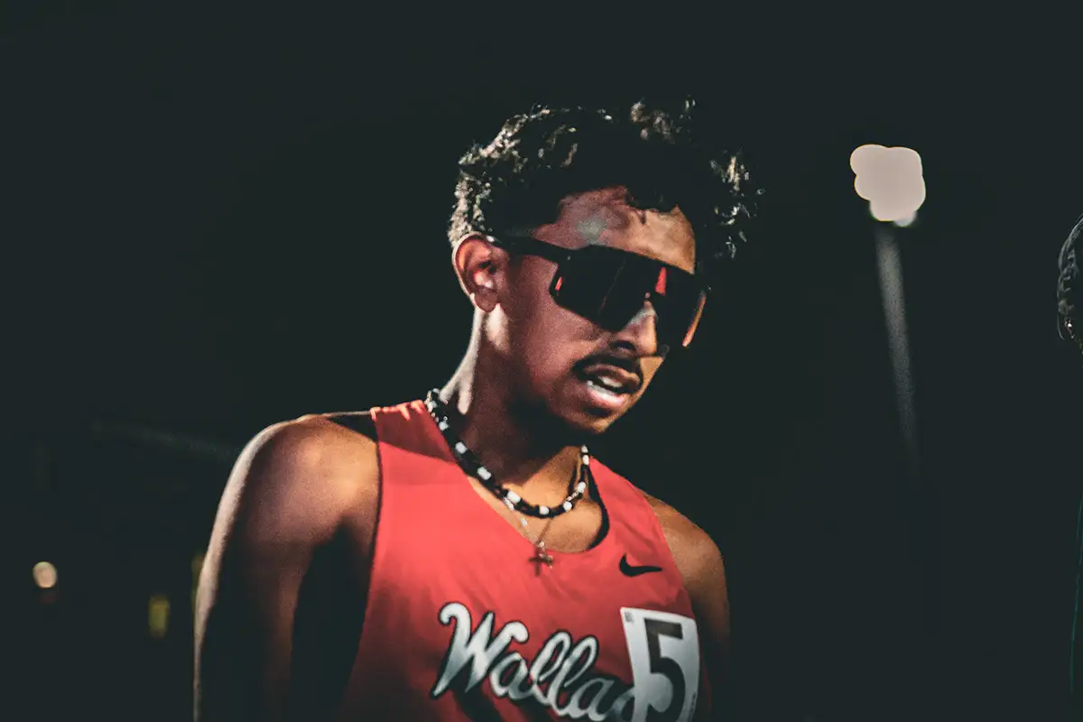 Runner in sunglasses and a red jersey against a dark background