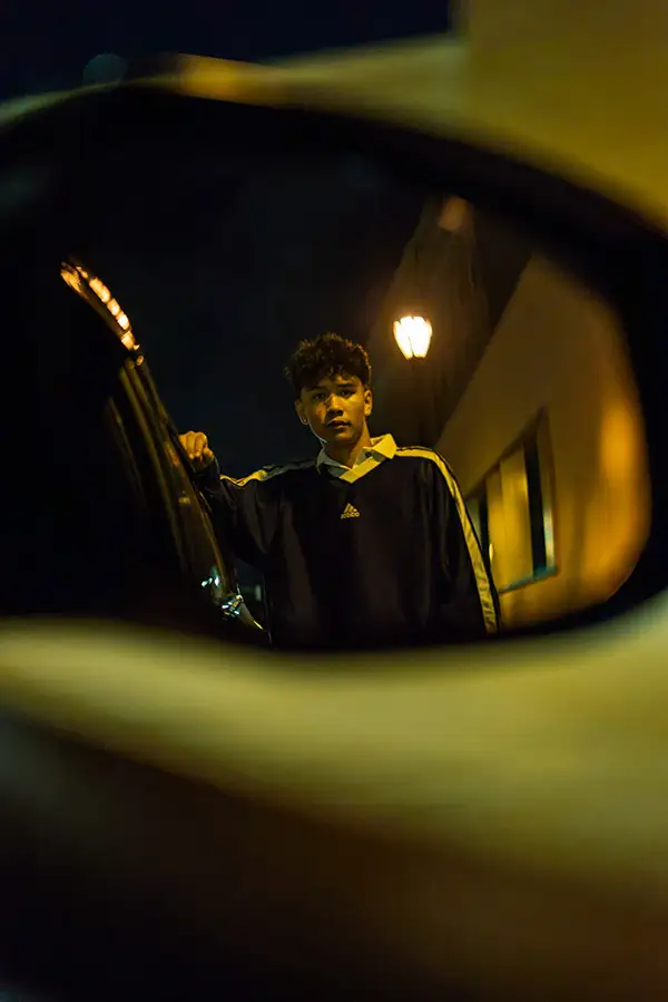 Young man at night framed through a car's side mirror
