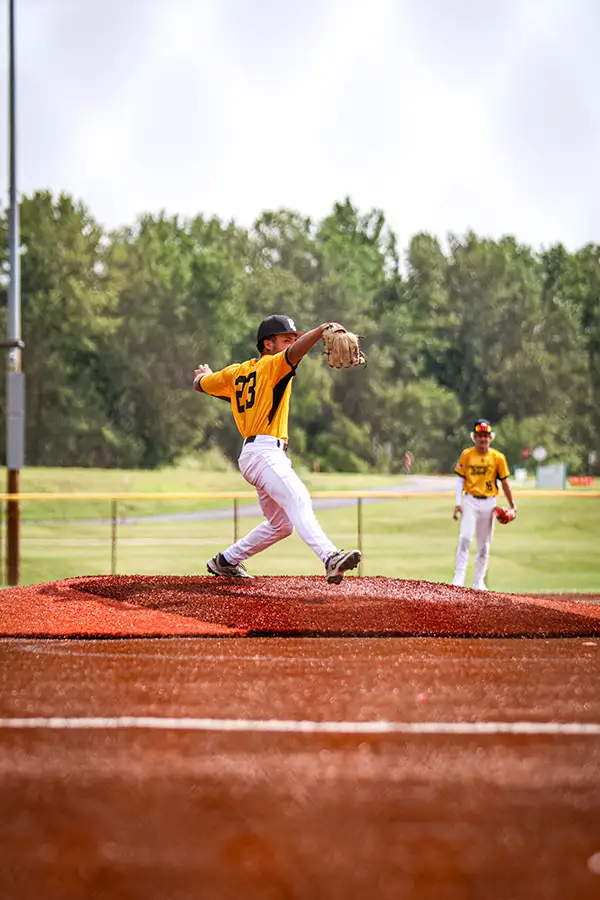 Pitcher in a yellow uniform throwing from the mound
