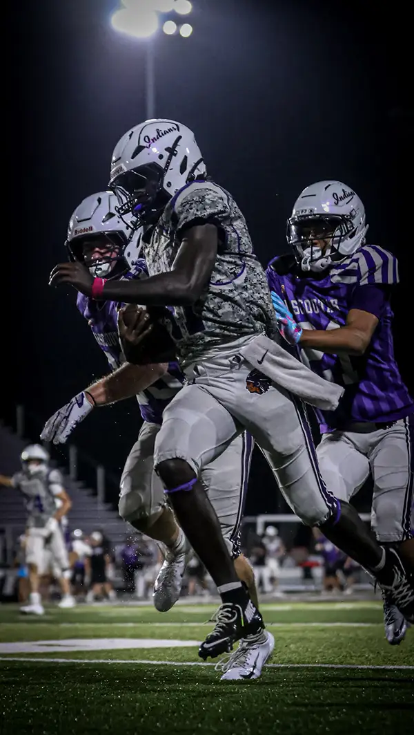 Football players colliding under stadium lights at night