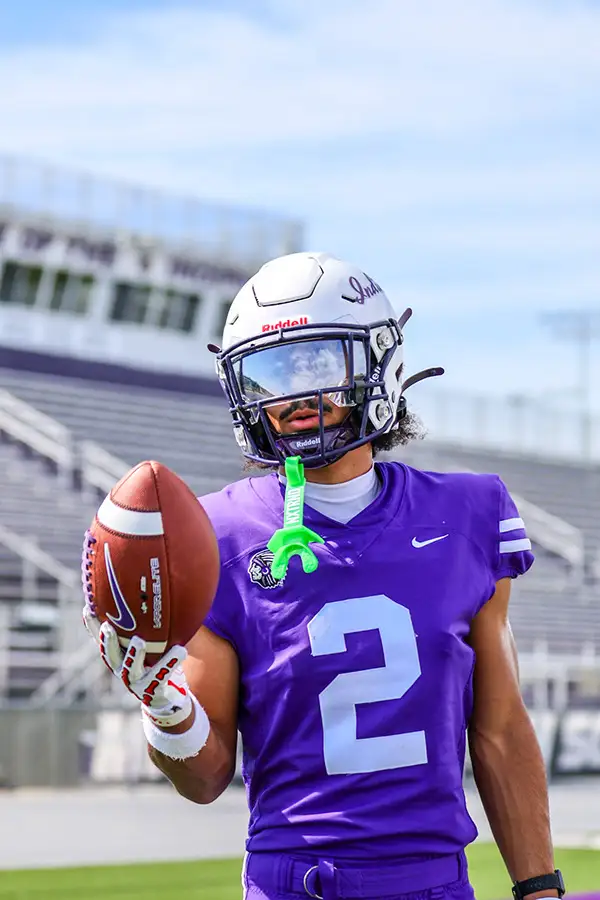 Football player in a purple number 2 jersey holding up the ball